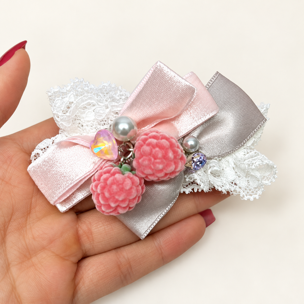 Pink berry charms on white lace and light-pink ribbon bows with a silvery sheen