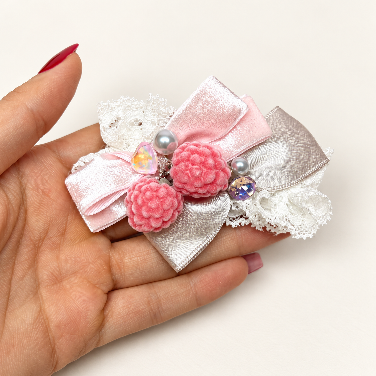 Pink berry charms on white lace and light-pink ribbon bows with a silvery sheen