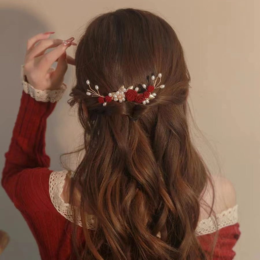 Red rose and pearl hair accessory styled in softly curled hair